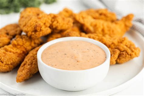 Thematic photo of crispy fried chicken strips on a plate with various dipping sauces