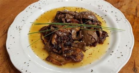 Pripravljena telečja jetrca s čebulo in jurčki na krožniku.