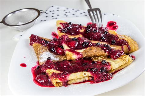 Tematska fotografija gratiniranih palačink s sadjem, posutih s sladkorjem v prahu