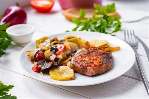 Thematic photo of cooked pork steaks with various vegetables on a plate
