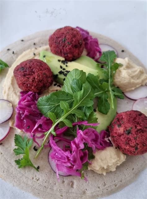 Prikaz kulinaričnega krožnika s falafli in orientalskimi namazi.
