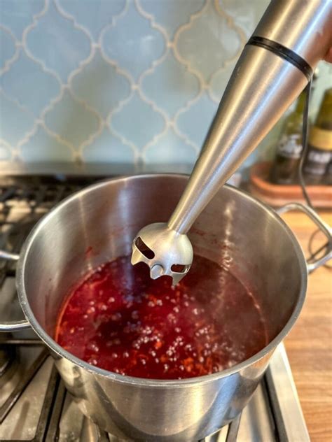 Photo of plum jam being pureed with an immersion blender