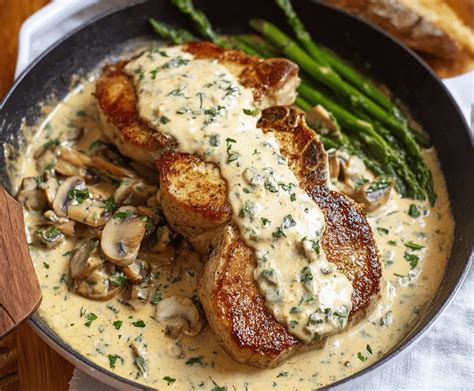 Thematic photo of golden-brown pork chops with a rich creamy sauce, garnished with fresh herbs.