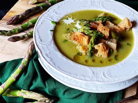 Pripravljena kremna špargljeva juha v krožniku, okrašena z vršički