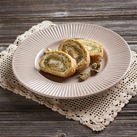 Prikaz končne rolade z bučnimi semeni, narezane na rezine, postrežene s svežim sadjem.