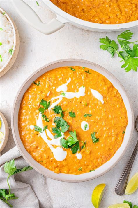 Detailed photo of red lentil curry with coconut milk, garnished with fresh herbs