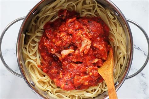 Thematic photo of pasta with tuna and tomato sauce, garnished with fresh herbs