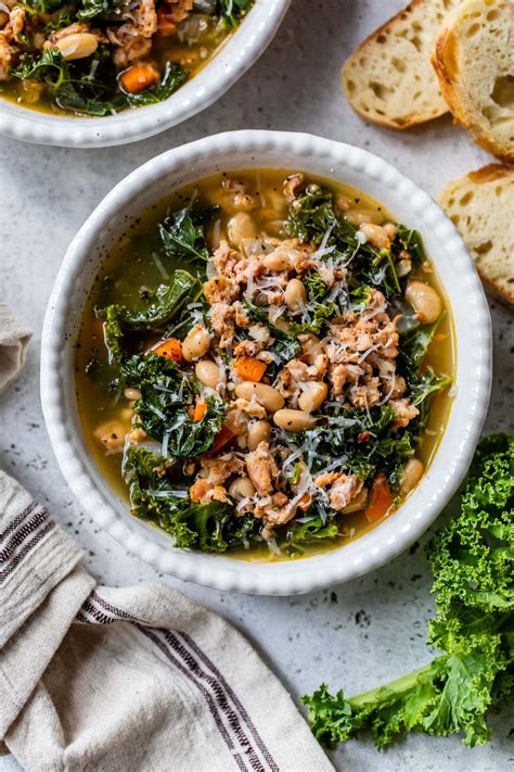 Thematic photo of a bowl of kale soup on a wooden table with fresh kale leaves