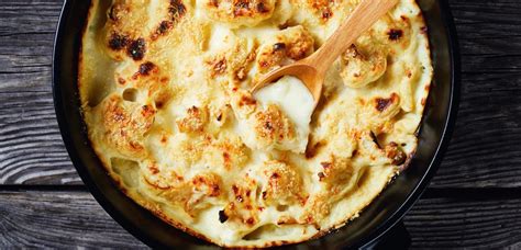 Zapečena cvetača v kremasti sirovi omaki, posuta z zelišči.