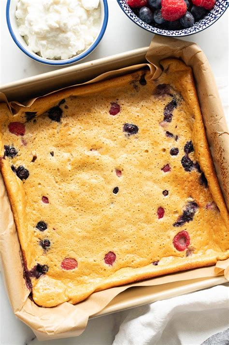 Thematic photo of a baked cottage cheese pie with forest fruits, cooling on a wire rack.