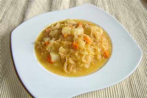 Serviranje golaževe juhe s krompirjem, okrašene s kislo smetano in drobnjakom