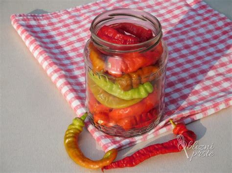 Fotografija različnih vrst vloženih feferonov v kozarcih.