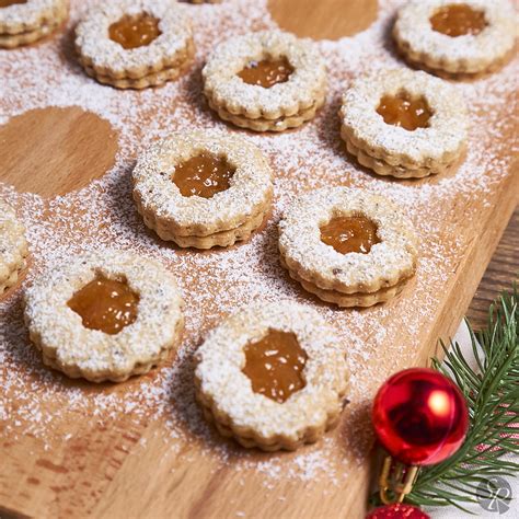 Ilustracija krhkih piškotov z mandlji in marmelado, potresenih s sladkorjem v prahu.