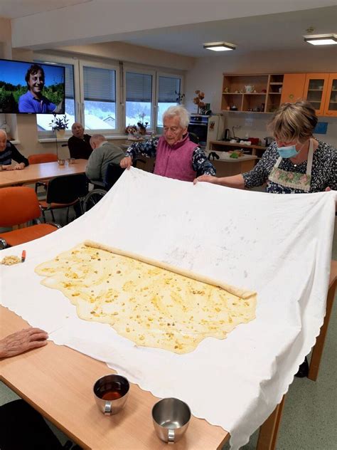 Priprava štrukljev, prikaz zvijanja testa z nadevom na peki papirju.