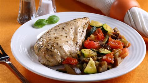 raznobarvna zelenjava in piščančji fileji enakomerno razporejeni po pekaču, pripravljeni za peko