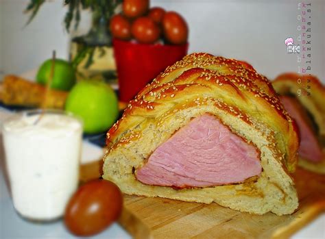 Ilustracija pečene šunke v zlatorjavem kruhovem testu, okrašena z vejico rožmarina.