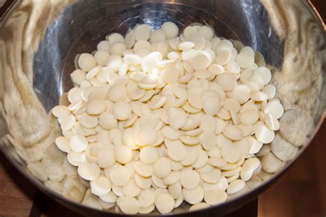 Tematska fotografija kakovostne bele čokolade v kapljicah ali narezane na koščke, pripravljene za topljenje