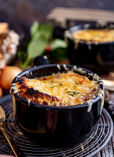 Ognjevarne posodice s čebulno juho, pokrite s sirom in pripravljene za peko v pečici.