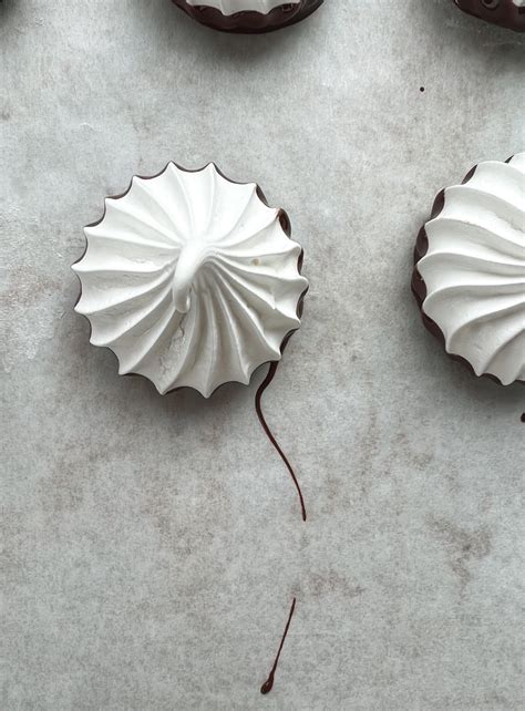 Fotografija beljakovih kupčkov (meringue) na peki papirju pred peko.