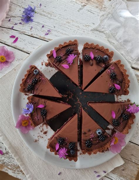 Fotografija plastovite torte iz gozdnih sadežev brez pečenja, z rezinami keksov in smetano.