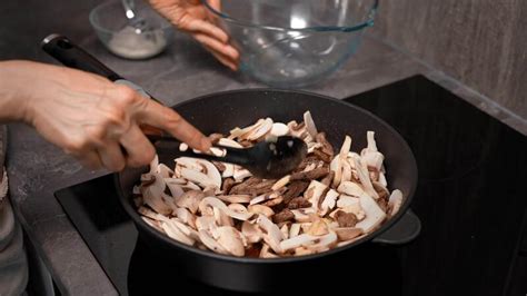 A close-up of mushrooms and onions sizzling in a pan