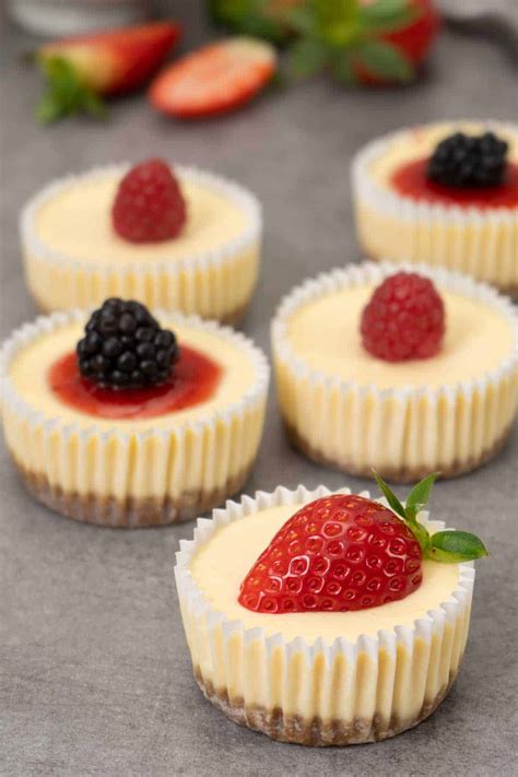 Individual mini cheesecakes in glasses, decorated with berries.