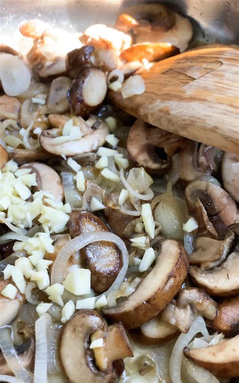 Close-up photo of sautéing shallots, garlic, and mushrooms in a pan.