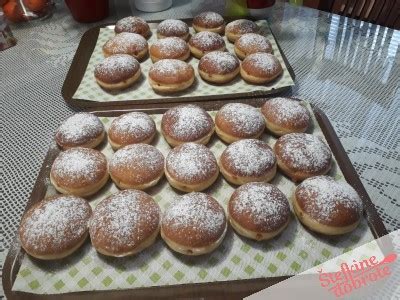 fotografija dokončanih krofov, posutih s sladkorjem v prahu in z nadevom