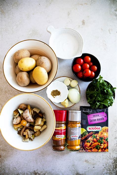 pripravljen krompirjev curry v skledi, okrašen s svežimi zelišči in češnjevim paradižnikom