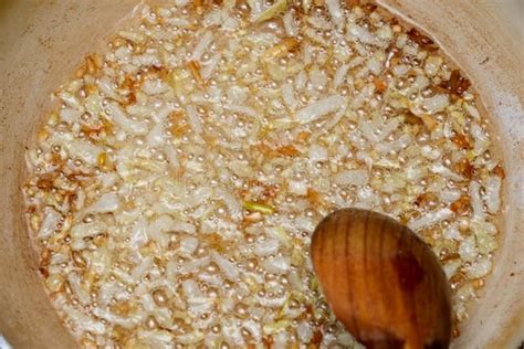 Image of chopped onions caramelizing in a pot, with raw veal cubes