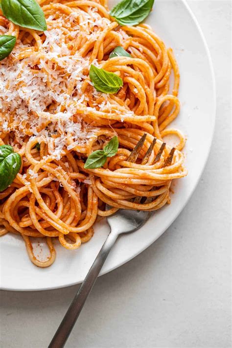 The final dish of spaghetti with a creamy vegan sauce made from cashews, sun-dried tomatoes, and basil, garnished with roasted broccoli and fresh herbs.