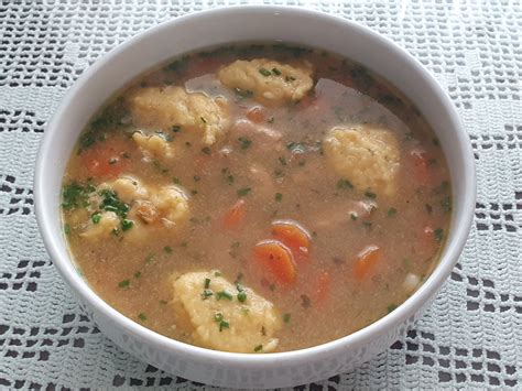 Tradicionalna slovenska kisla juha v keramični skledi, okrašena s svežim peteršiljem.