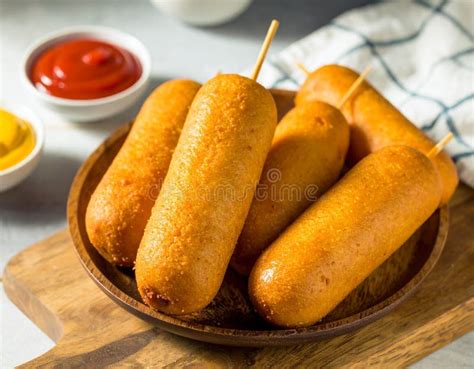 Thematic photo of several corn dogs on sticks with dipping sauces