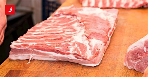 kuhar nareže svinjsko ribico na trakove na leseni deski