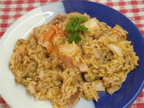 Pripravljena rižota z morskimi sadeži in grahom, postrežena v krožniku.