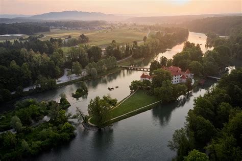 Panoramski pogled na Grad Otočec ob reki Krki, obdan z zelenjem