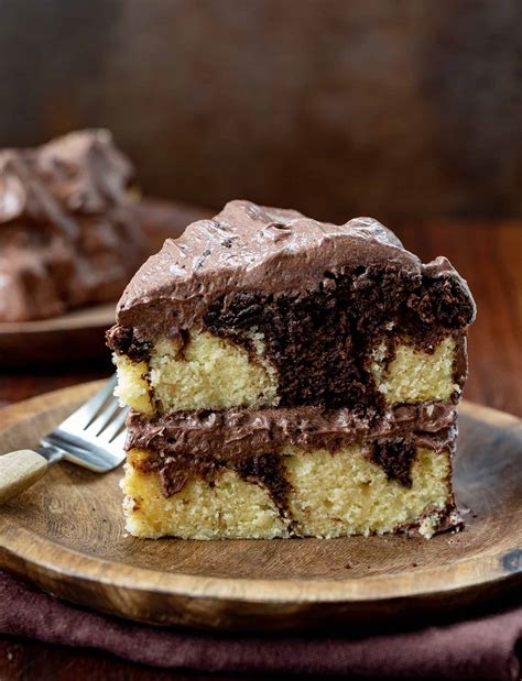 Thematic photo of a beautiful, freshly baked marble cake, with a visible LCHF texture, placed on a wooden cutting board with a slice cut out.