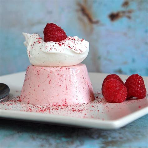 Thematic photo of panna cotta with raspberry topping on a white plate, garnished with mint leaves