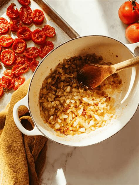 Photo of a pot with sautéing onions, tomatoes, and basil.