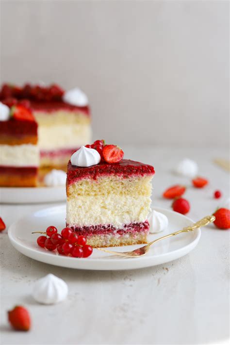 Fotografija torte z belo kremo in kokosovo moko, okrašene z belimi čokoladnimi kroglicami.