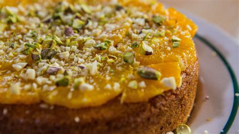 Fotografija okrogle torte iz polente, okrašene s pomarančnimi rezinami in mandlji