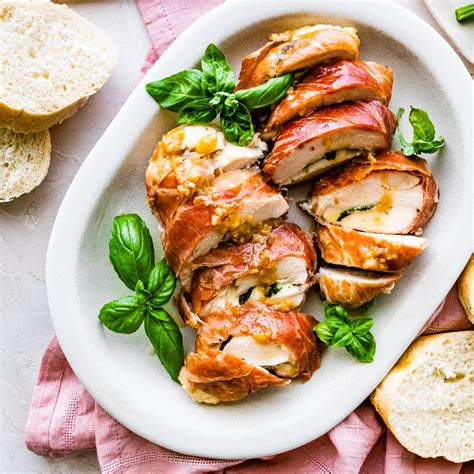 Thematic photo of chicken fillet with tomatoes and cheese wrapped in foil, ready to bake
