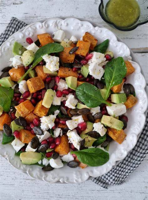 prikaz barvite solate s pečenim sladkim krompirjem, orehi in feta sirom v veliki skledi