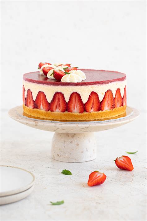 Okusna torta z jagodami in kremo, okrašena s cvetovi.