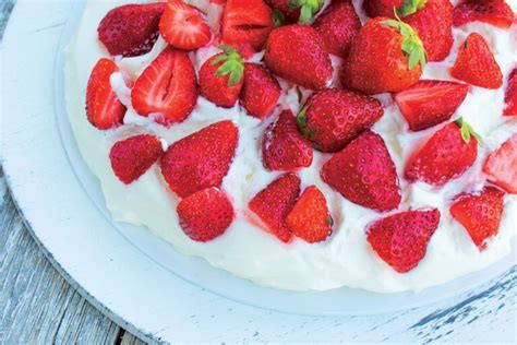 Pavlova torta z jagodami, smetano in metinimi lističi.