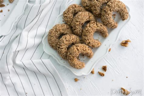 Thematic photo of small, irregular walnut meringue cookies (orehovi poljubčki) arranged on a plate, possibly with some decorative elements resembling sea pebbles.