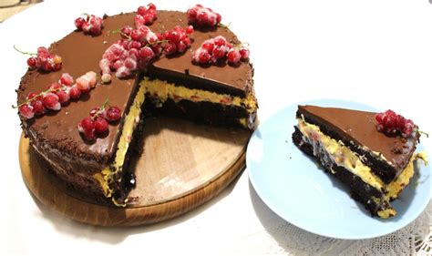 fotografija čokoladne torte, okrašene s svežim rdečim ribezom in stepeno smetano