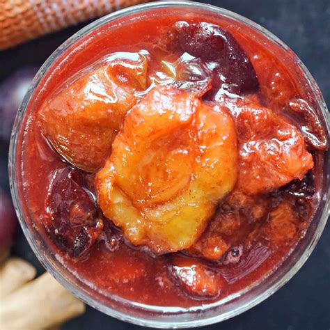 Thematic photo of a bowl of fresh apple and plum compote with cinnamon sticks