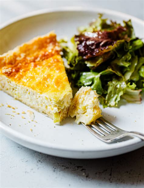 Thematic photo of a slice of leek pie with rice on a plate, possibly with yogurt or salad on the side.