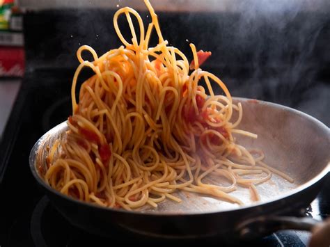 Thematic photo of pasta being mixed with sauce in a pan